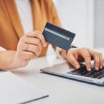 Person holding a credit card while using a laptop.