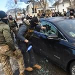 ICE officers breaking a car window to remove a woman from her vehicle on January 13, 2026 in Minneapolis, Minnesota.