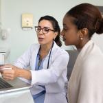 A young black woman going over medical examination results with her female doctor.
