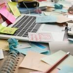 Sticky notes mess on top of a laptop on a working desk.