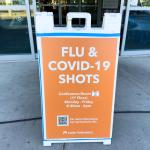 Flu and COVID-19 sign outside a clinic entrance.