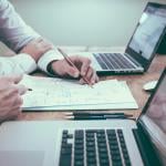 Businesspeople planning on paper in front of their laptop.s