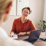 A female hiring manager happily interviewing a job candidate.