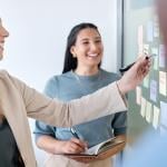 A business team planning for a project using sticky notes on a board.