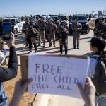 Texas State Troopers surrounded by protesters as they denounce detention of 5-year-old, Liam Ramos, at an immigration processing facility in Texas. One person holding a 'free the child, free all' sign put it up facing the troopers.