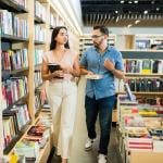 A young woman and man walking together at a bookstore and shopping for books.