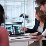 A business team reviewing billing reports displayed from a laptop.