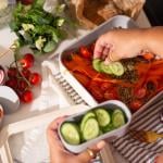 Vegetables being added on top of a healthy meal prep dish.