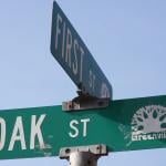An intersection sign for a First Street and Oak Street.