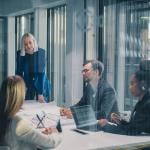 A business team inside a glass meeting room.