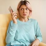 An annoyed woman holding her smartphone due to an unexpected call.