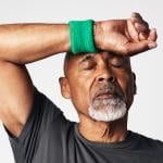 A senior black man wiping off sweat from his forehead.