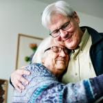 A senior couple dancing together in their home.