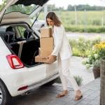 A businesswoman picking up parcels from the trunk of her car.