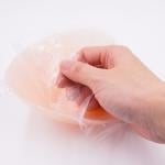 Film adhesive being peeled off a silicone bra pad.