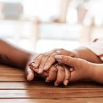 A couple's hands holding each other as an act of empathy.