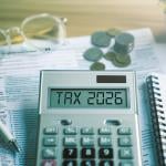 Calculator showing 'tax 2026' over tax documents.