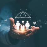 Person's hand holding hologram graphics of a family with an umbrella as a concept of life insurance.