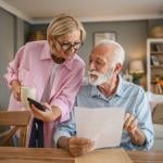 A senior couple reading a document and checking information online together.