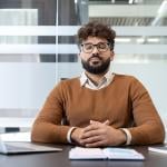 A man with eyes closed meditating at his office desk.