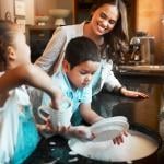 A mother with her two children washing dishes in the kitchen.