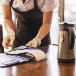 A restaurant waiter collecting the bill from a customer's table.