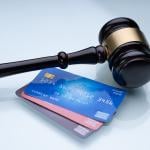 A gavel and a few credit cards laid on a table.