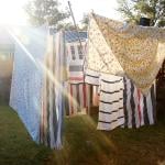 Washed sheets hanging from clothesline to dry under the sun.