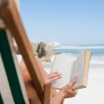 A woman reading a book at the beach.