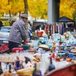 A seller preparing antique items for sale at a flea market in Paris, France.