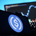 A stablecoin logo displayed on a smartphone.