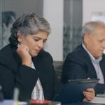 Two senior businesspeople reviewing reports at an office.