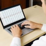 An accountant using a laptop showing financial statement spreadsheets and account balances.