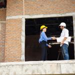 An architect and contractor shaking hands on site for a project.