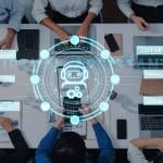 A top view of professionals engaging around a table, while using virtual assistant technology in a meeting.