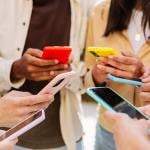A group of young people using smartphone forming a circle outdoors.