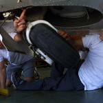 Aircraft mechanic students inspect a jet's landing gear.