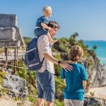 A father with his two sons enjoying the view of the pre-Columbian Mayan walled city of Tulum in Mexico.