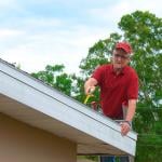 A wind mitigation inspector on a ladder doing inspection on a homeowner's new roof.