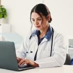 A female doctor using a laptop for a telehealth consultation.