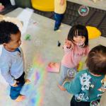 Young children playing with bubbles in day care. In the U.S., families spend between nine percent and 16 percent of their median income on full-day care for just one child.