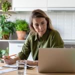 A female homeowner focused on reviewing documents at home.