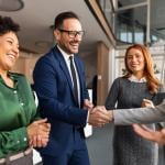 Coworkers engaging each other with handshakes in an office.