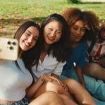 A group of four friends taking a selfie together outdoors.