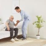 A nurse helping an elderly patient get out of bed in a nursing home. 
