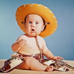 960s Baby Boy With Surprised Facial Expression Dressed As Cowboy Wearing Hat And Holster And Gun