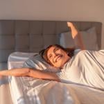 A happy young woman waking up in the morning.