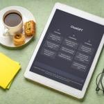 Webpage of ChatGPT on a tablet beside a cup of coffee and sticky notes.