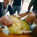 A senior basketball player injured during a game with teammates assisting. 