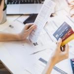 Woman looking at multiple credit cards and calculating debt expenses.